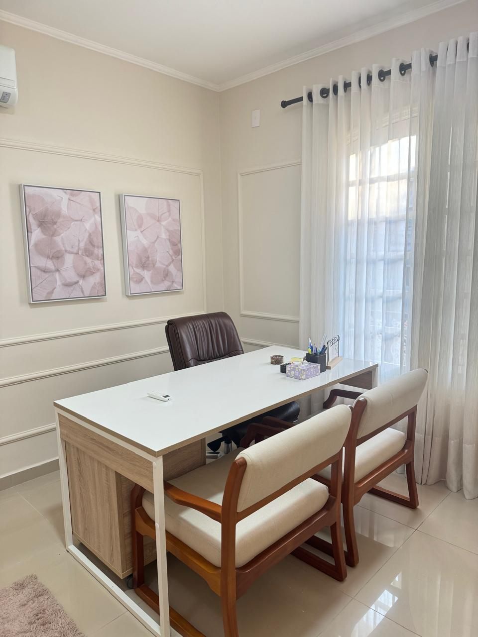 Consultório visto de outro ângulo, com janela e cortinas claras
